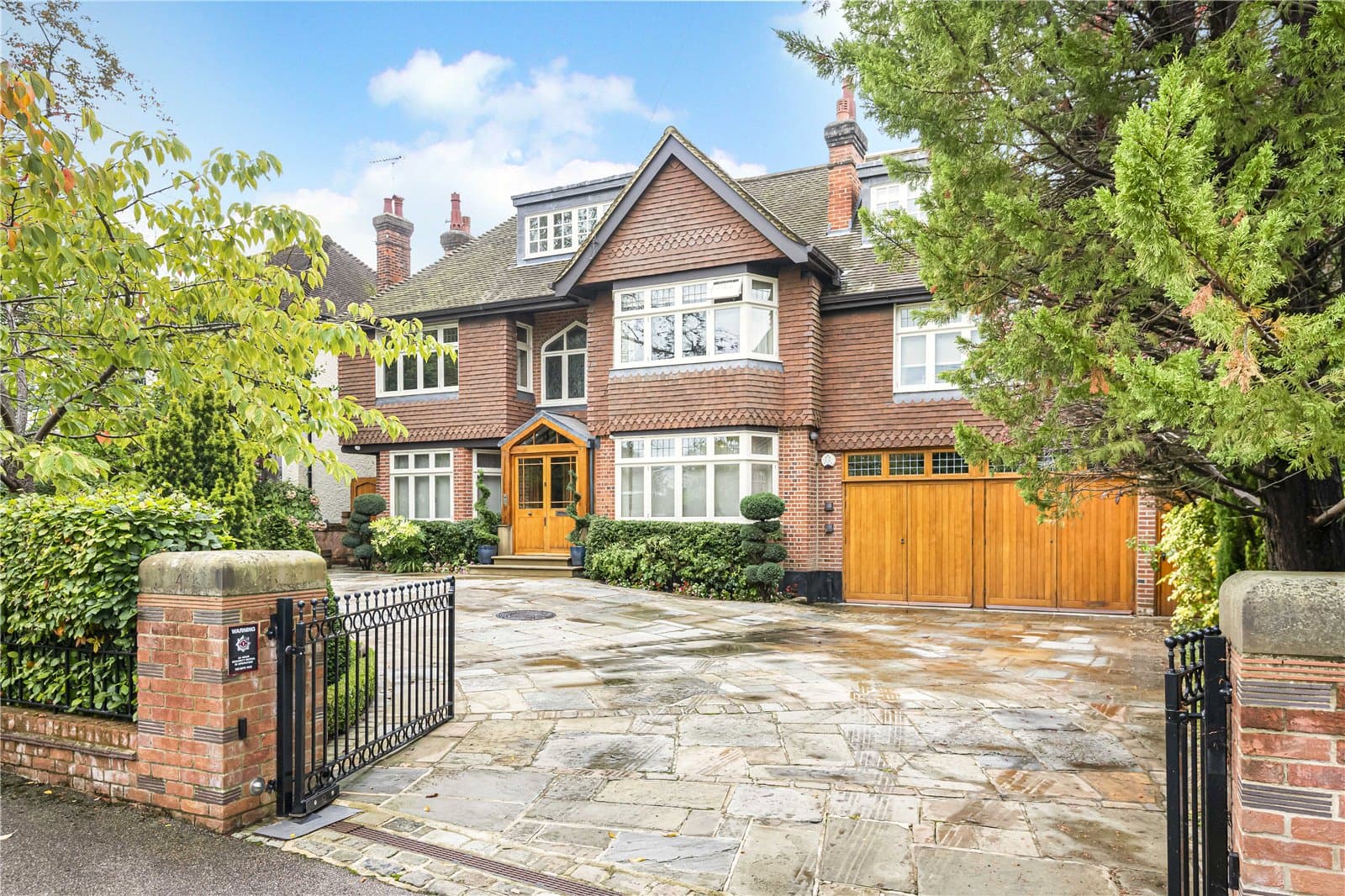 Exterior view of detached period residence on Grange Avenue in Totteridge with gated driveway, brick façade and integrated garage.