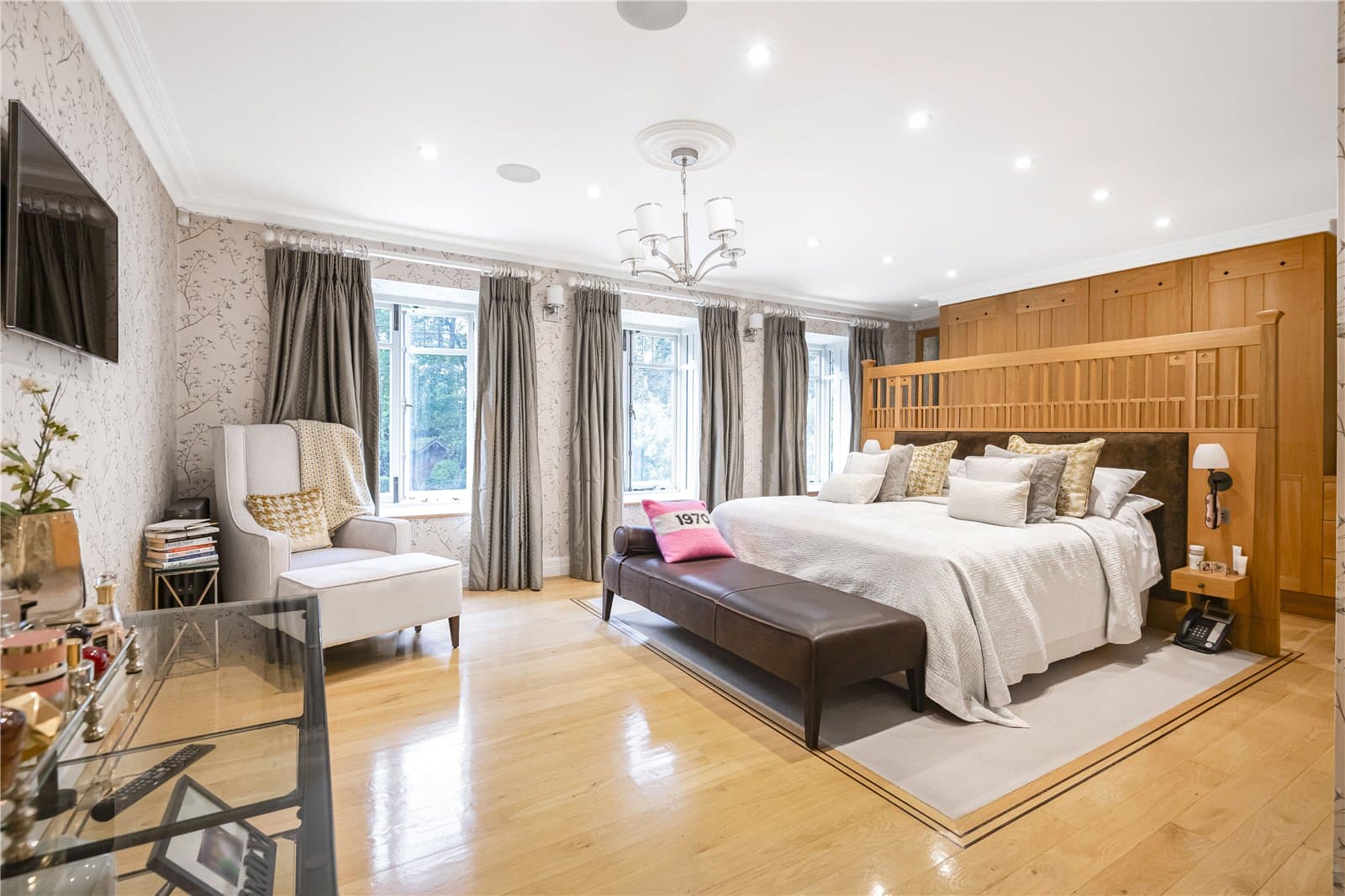 Principal bedroom suite with fitted wardrobes, seating area and large windows overlooking the garden.
