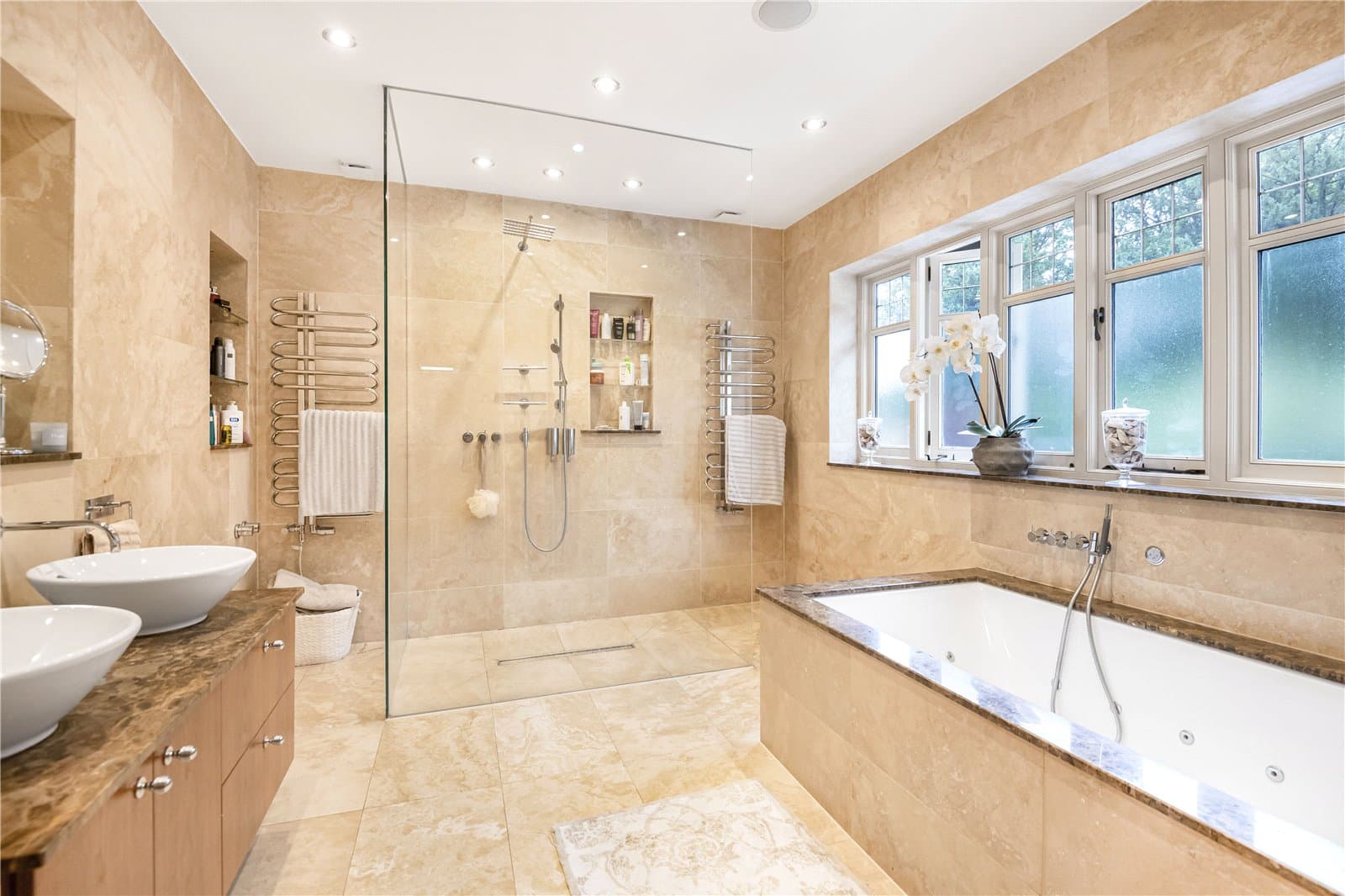 Luxury bathroom finished in natural stone with freestanding bath, walk-in shower and double vanity.