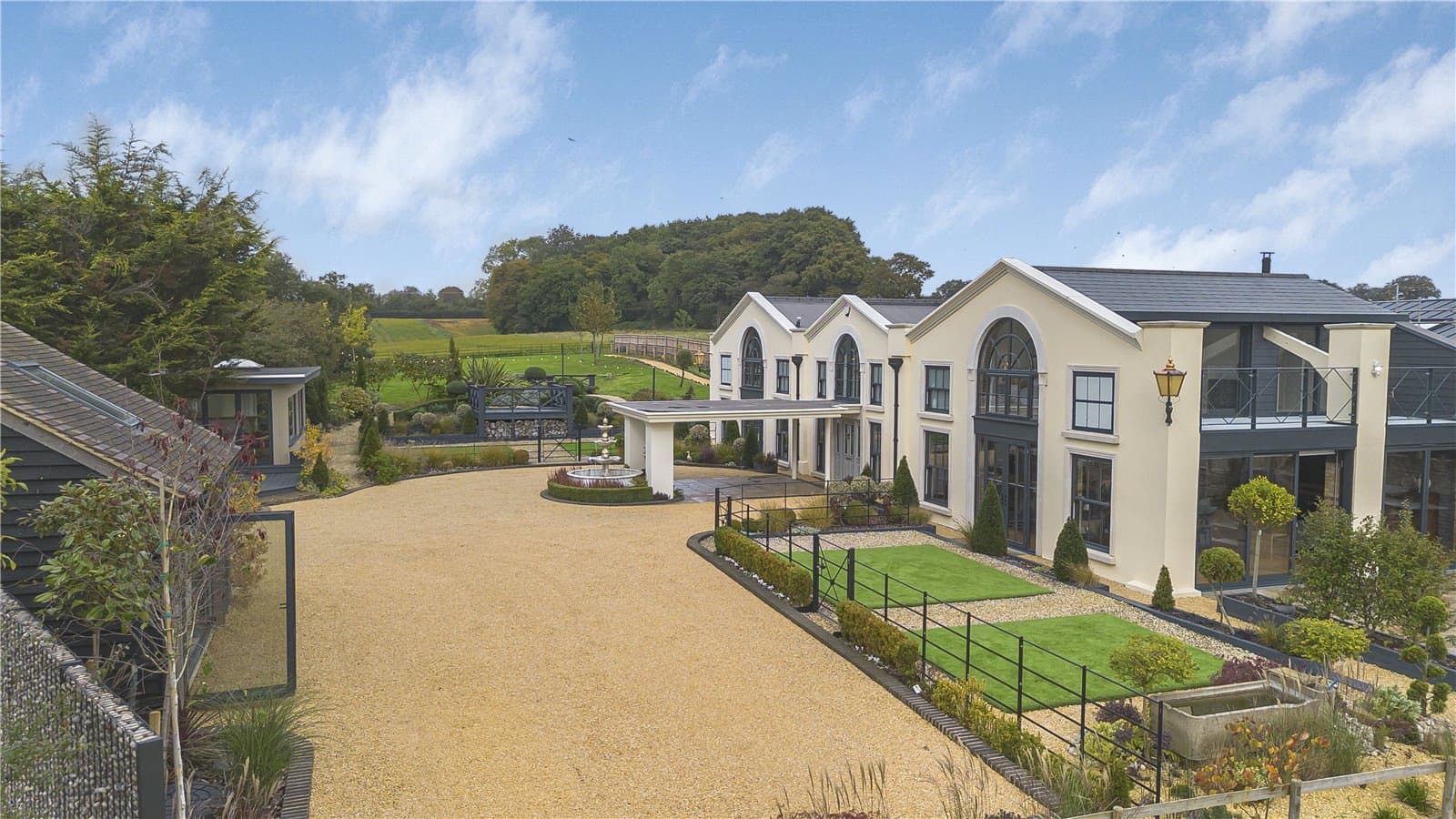 Elevated view of detached residence with landscaped gardens, gravel driveway and countryside backdrop in Theobalds Park