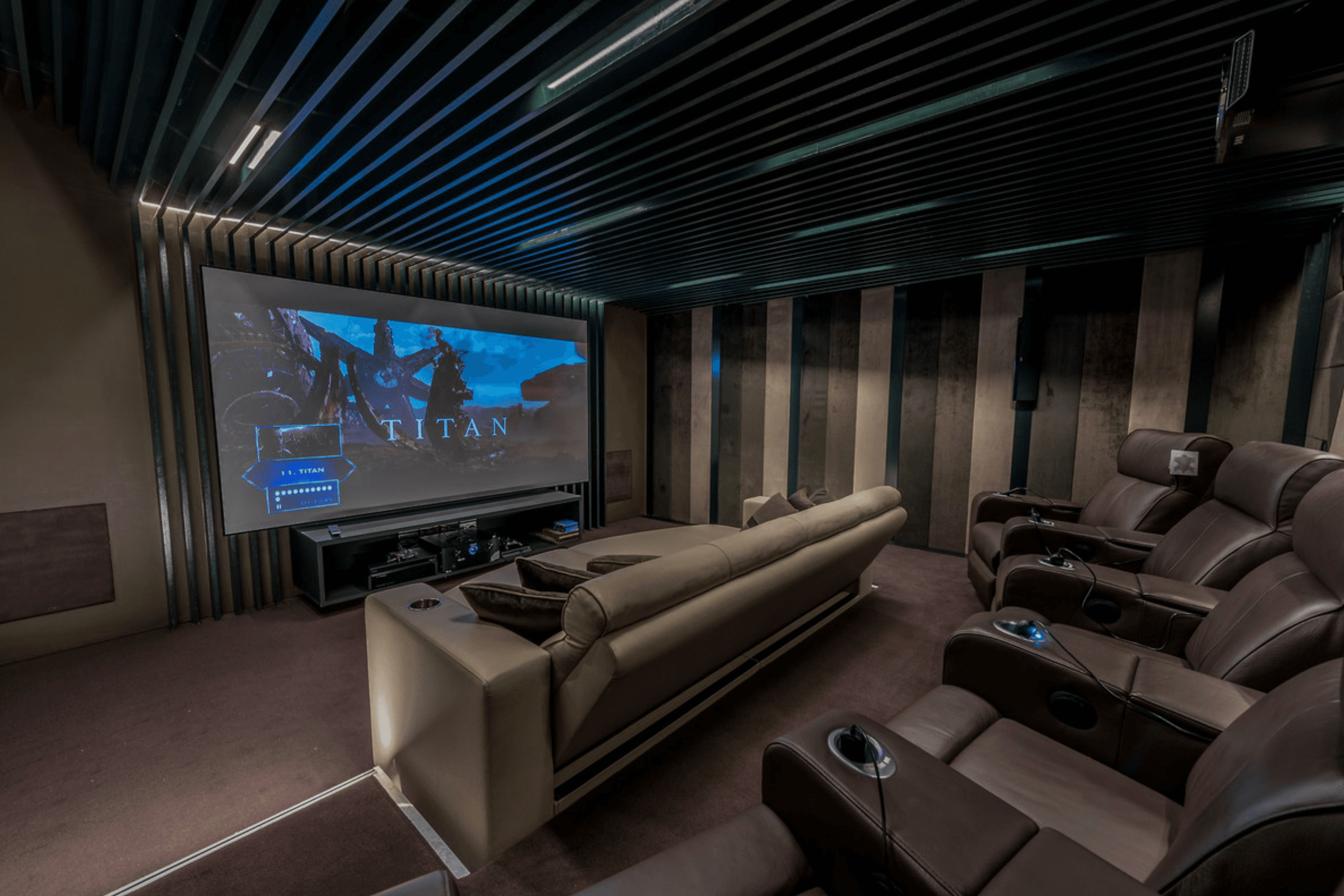 Private cinema suite with reclining leather seating, acoustic panelled walls and large projection screen.