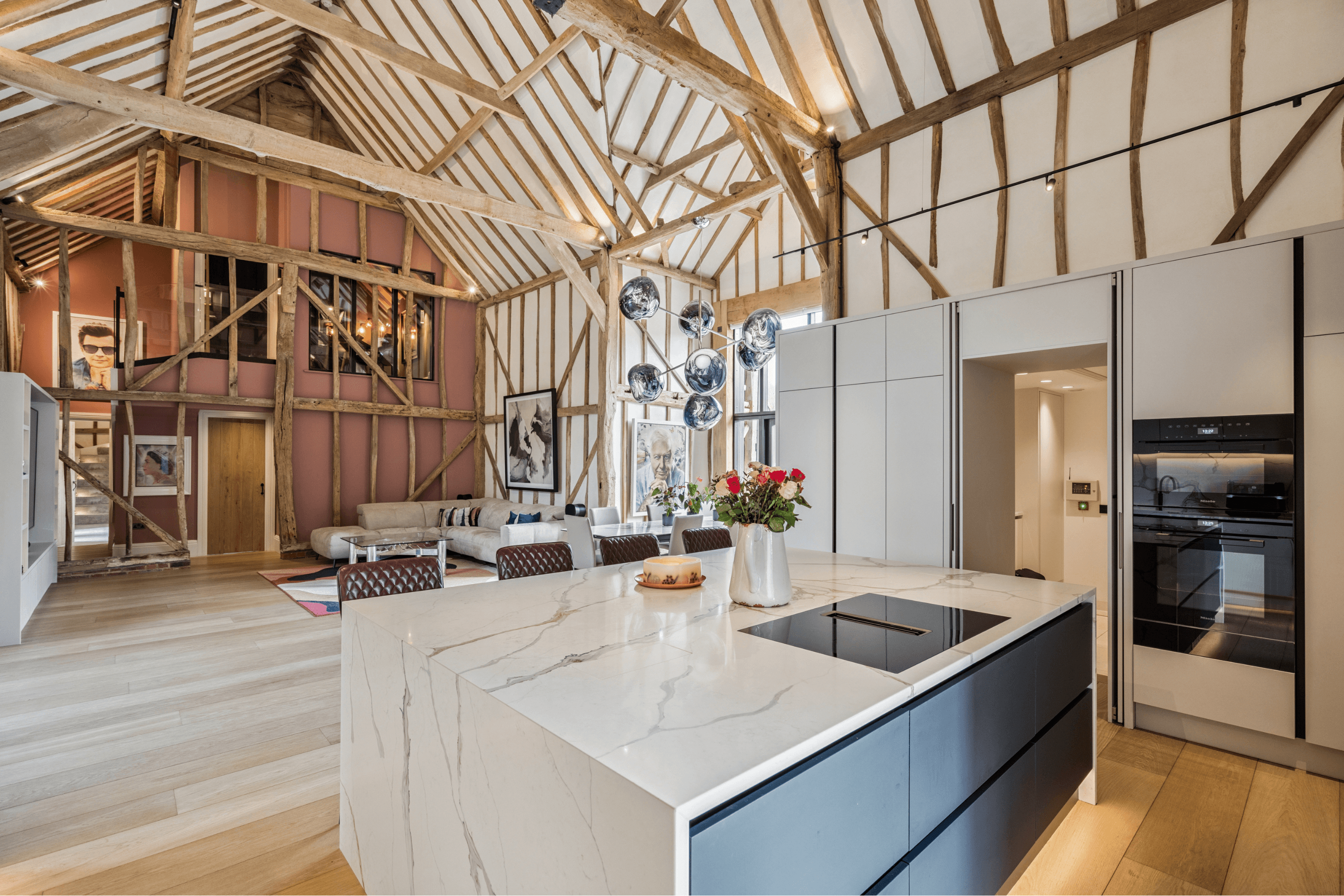 Bespoke shaker kitchen with marble island, integrated appliances and vaulted barn ceiling within the open-plan living space.