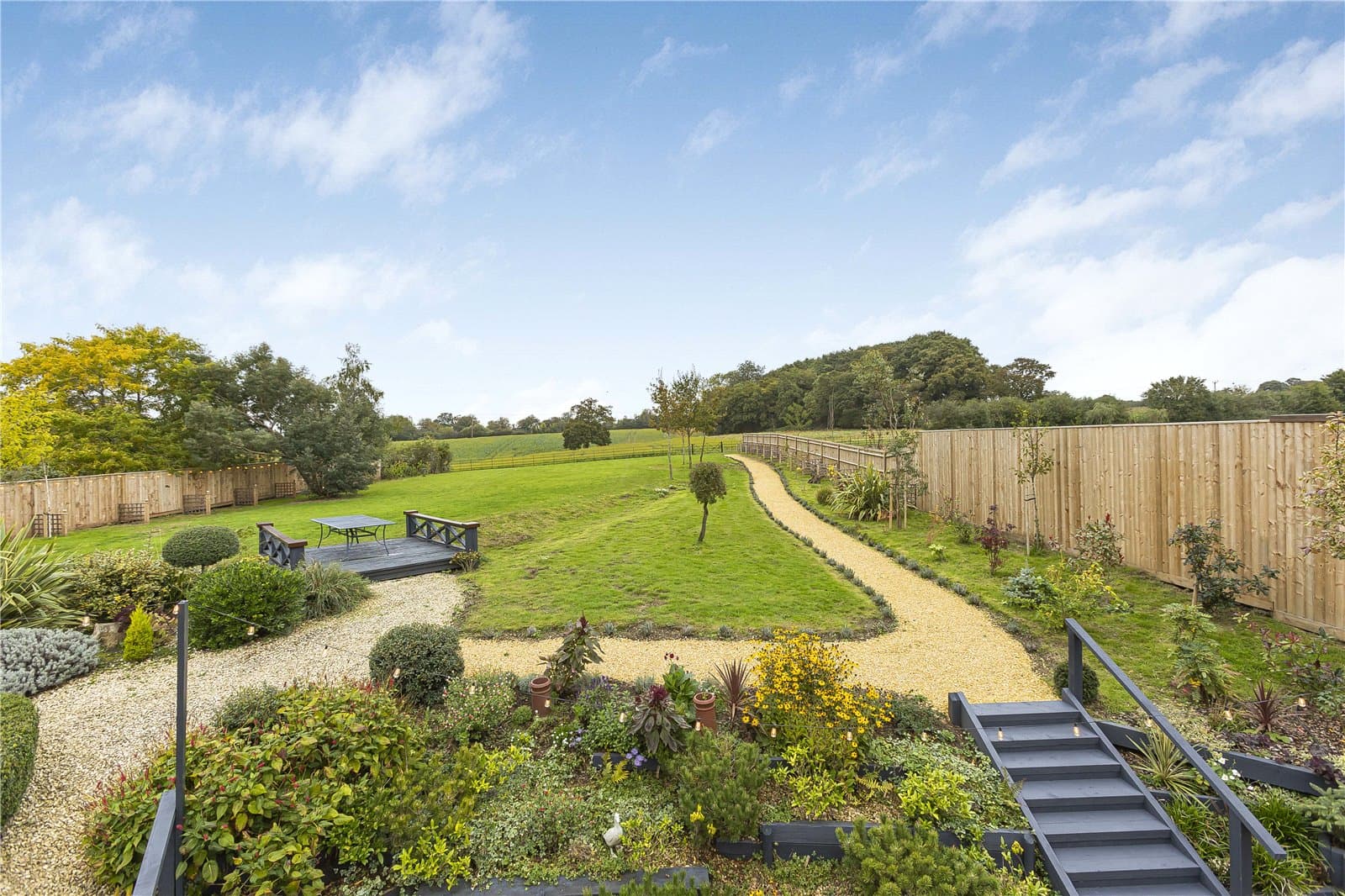 Landscaped rear garden with pathways, lawn and terrace overlooking open Greenbelt countryside in Hertfordshire