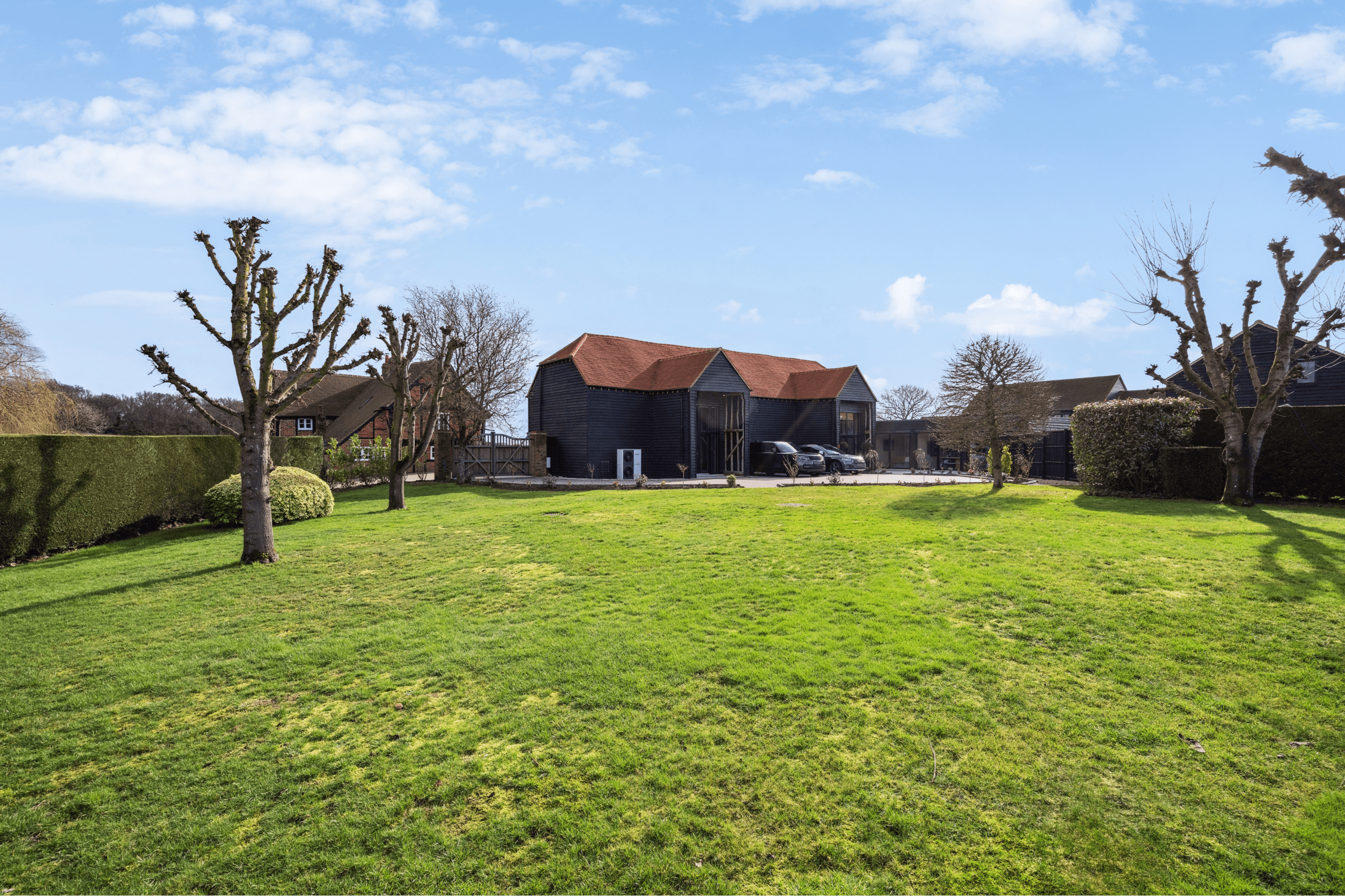 Wide view across the landscaped garden towards the restored barn and countryside beyond.