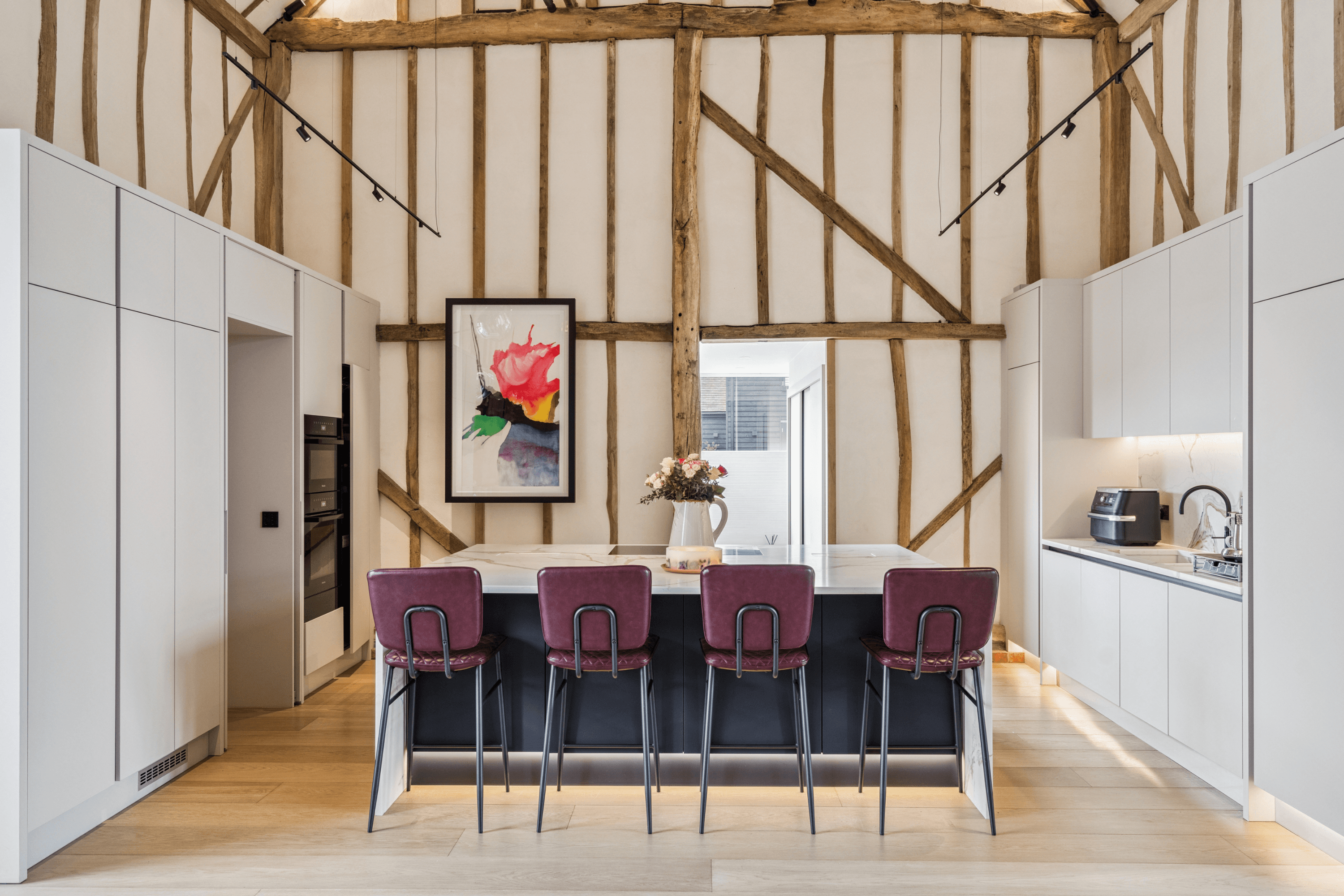 Kitchen island with breakfast seating set within the dramatic double height living space framed by exposed timber beams.