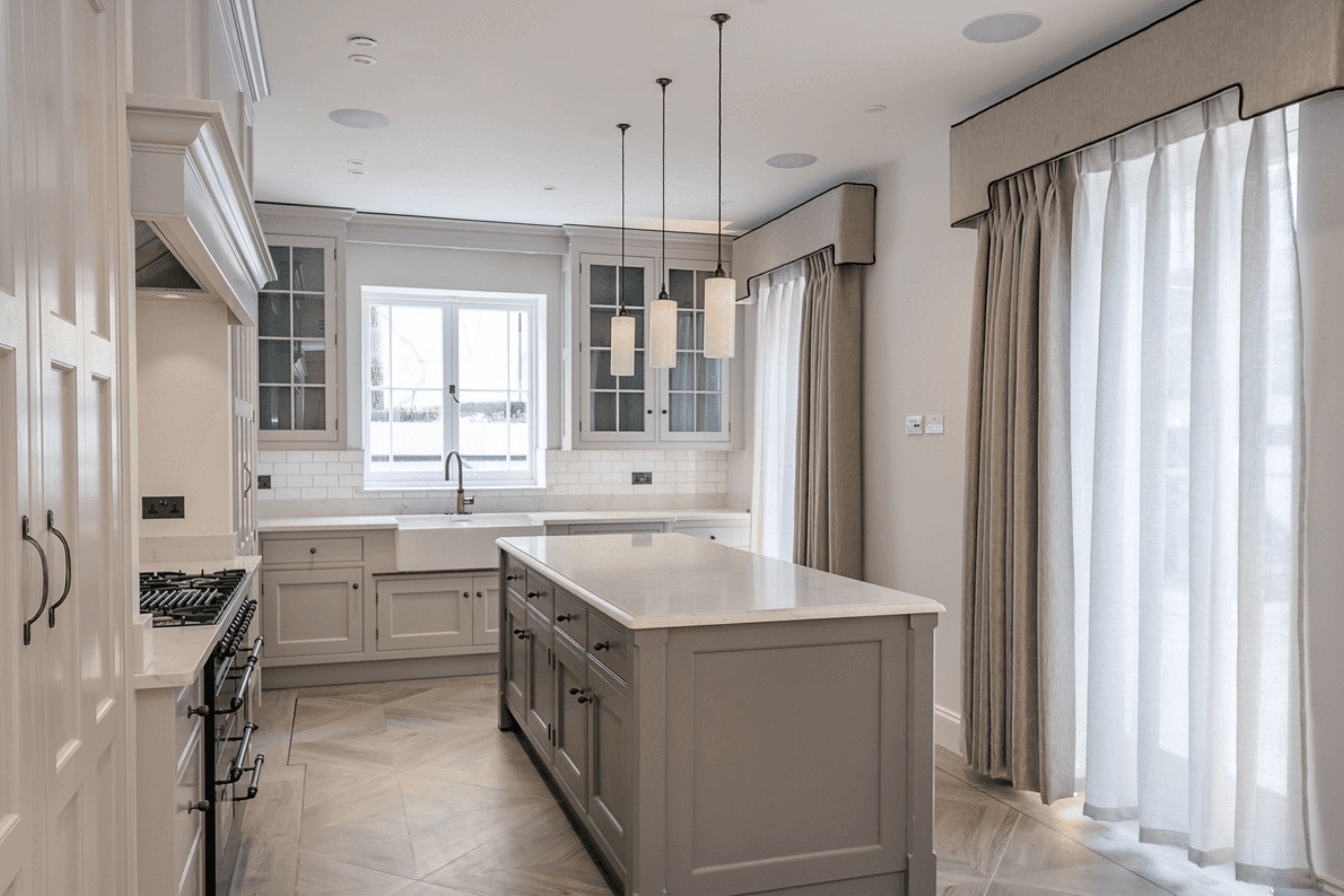 Shaker style kitchen with marble worktops, central island, pendant lighting and parquet flooring leading to rear garden access.
