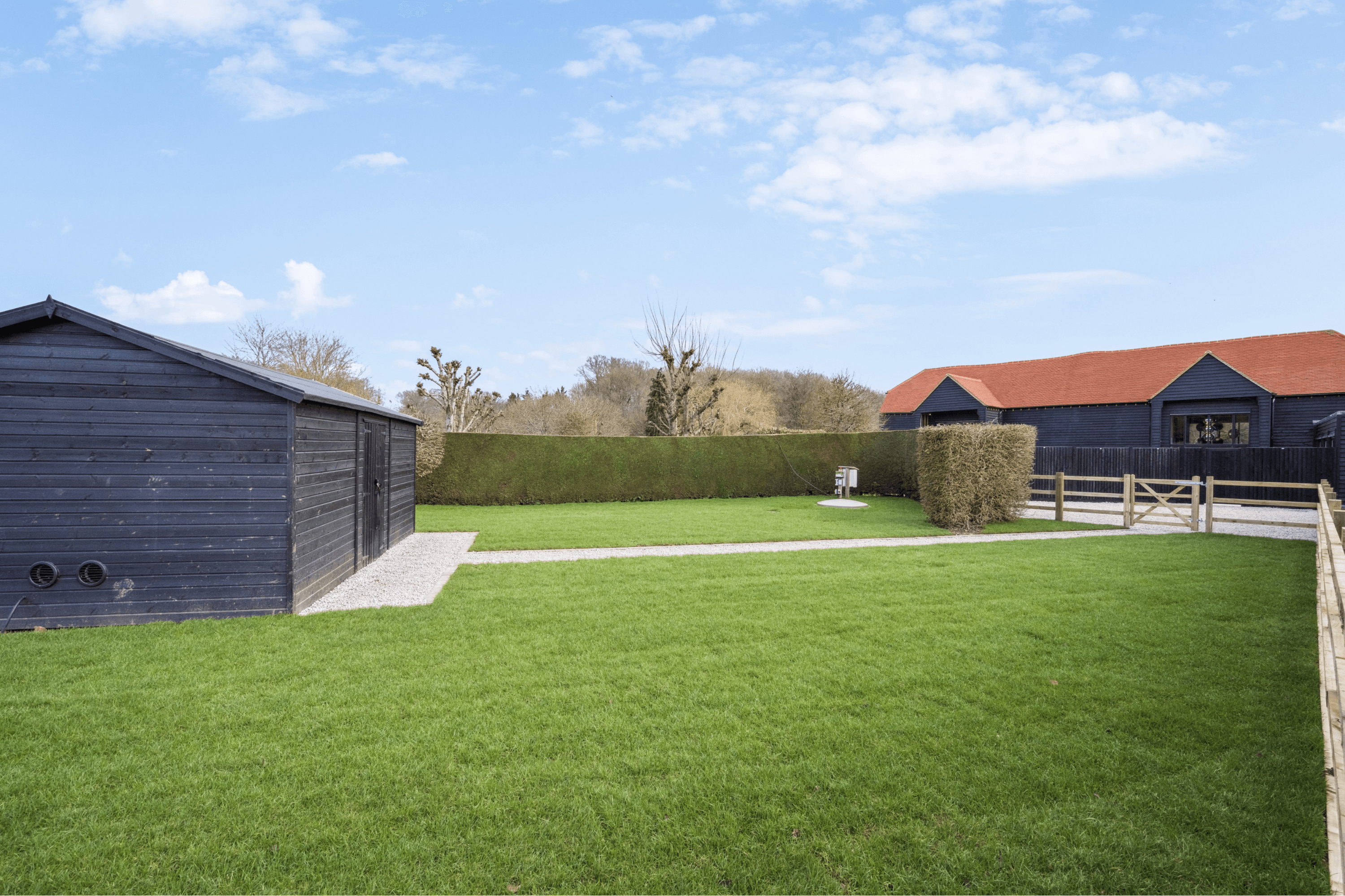 Private garden with lawn, hedging and timber outbuilding within the half-acre grounds of the barn conversion.