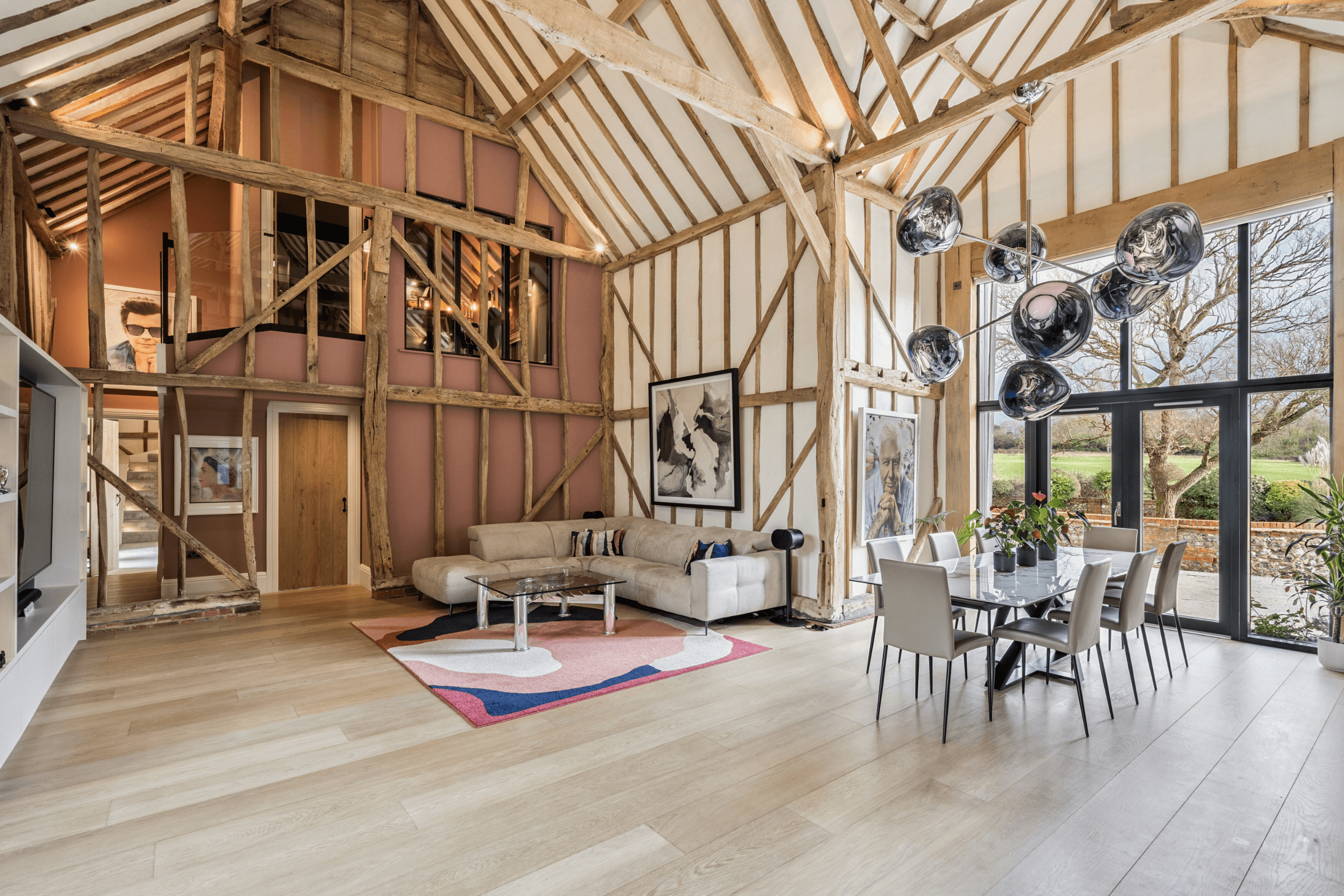 Wide view of the open-plan living and dining space showcasing the original timber frame structure and double height vaulted ceiling.