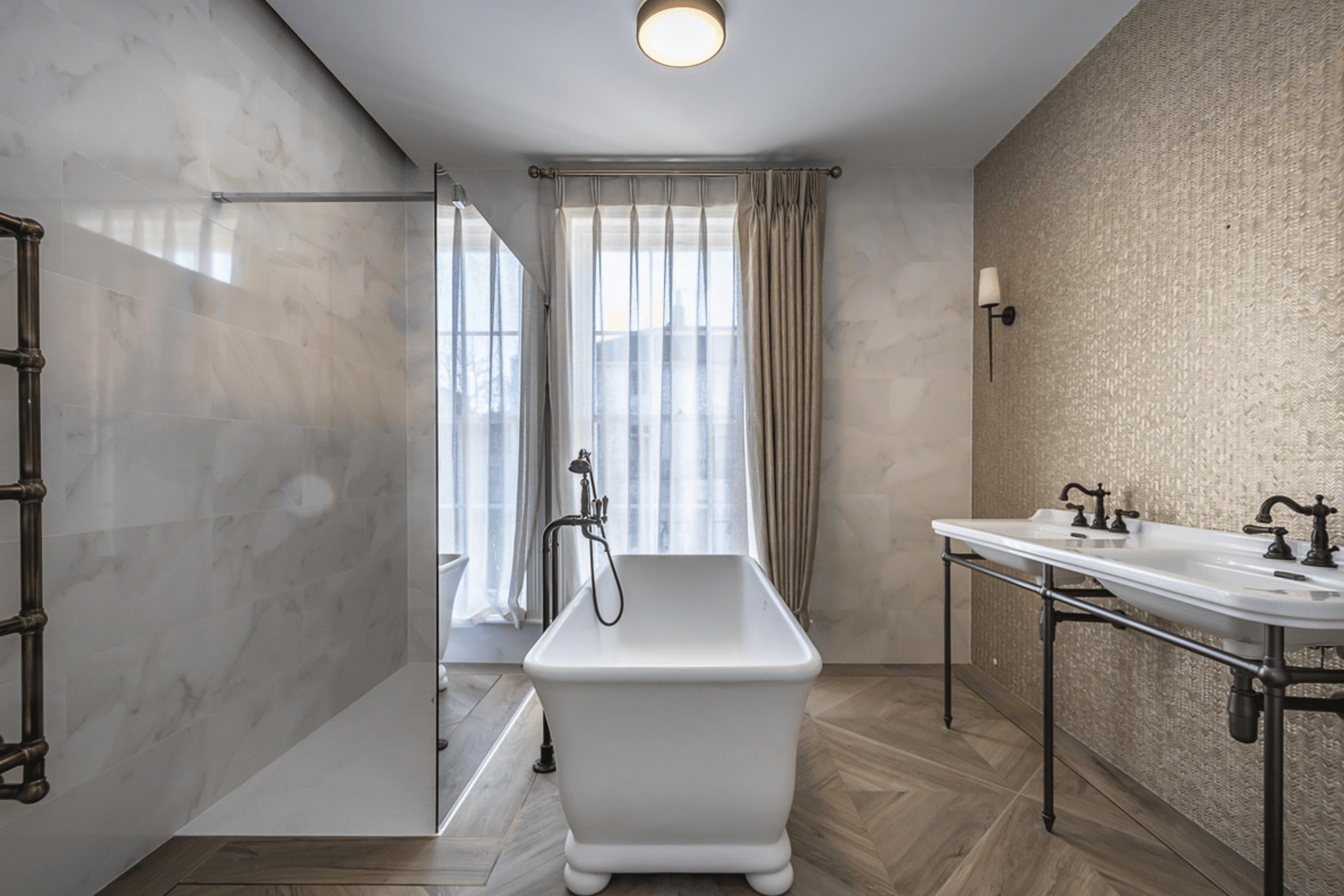 Marble bathroom with freestanding bath, walk in shower and twin basin vanity against textured wall finish.