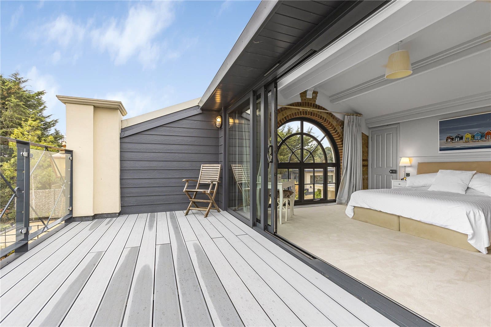 Principal bedroom opening onto a private balcony with glass balustrade and countryside views