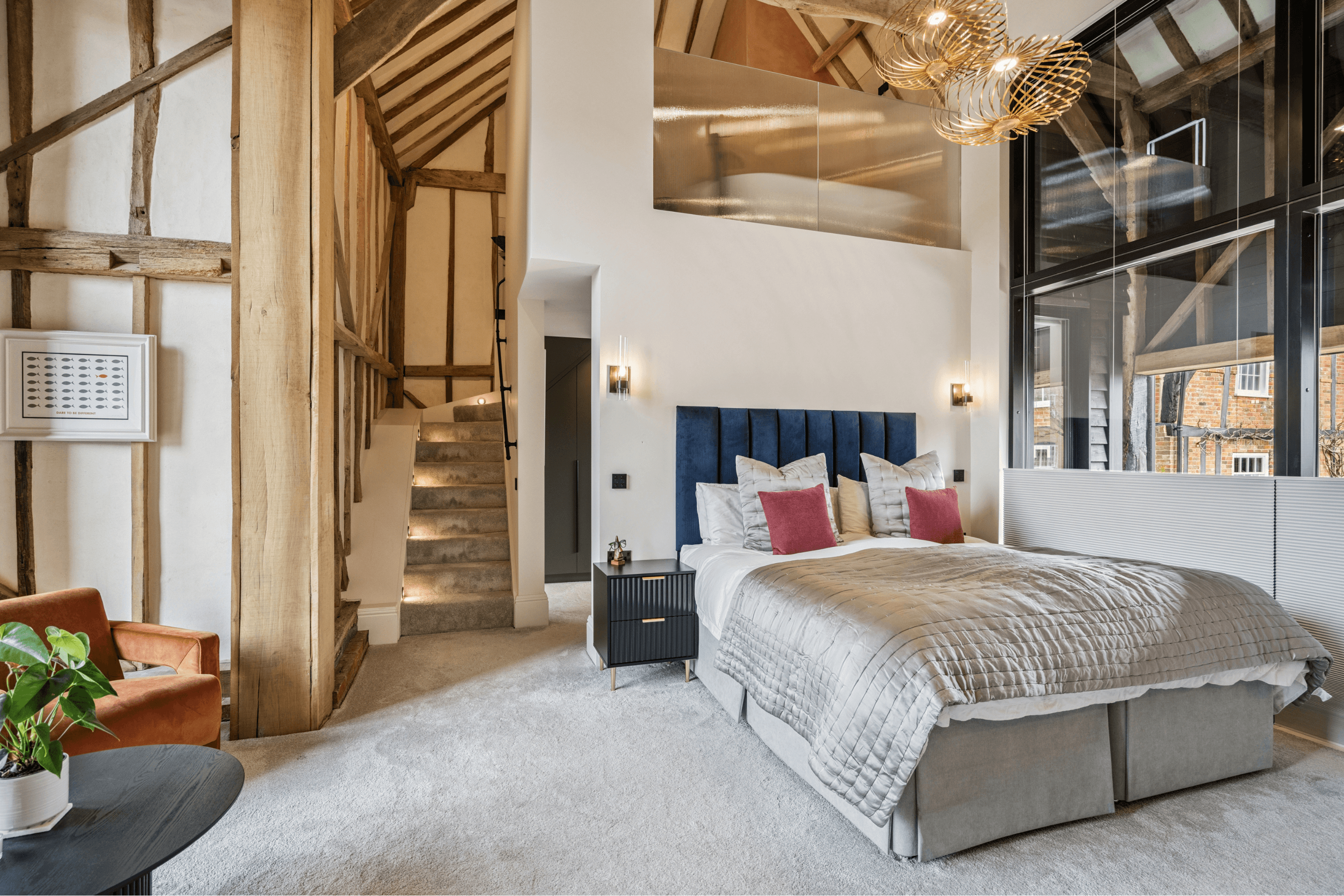 Principal bedroom suite featuring high vaulted ceiling, statement lighting and staircase leading to the upper level.