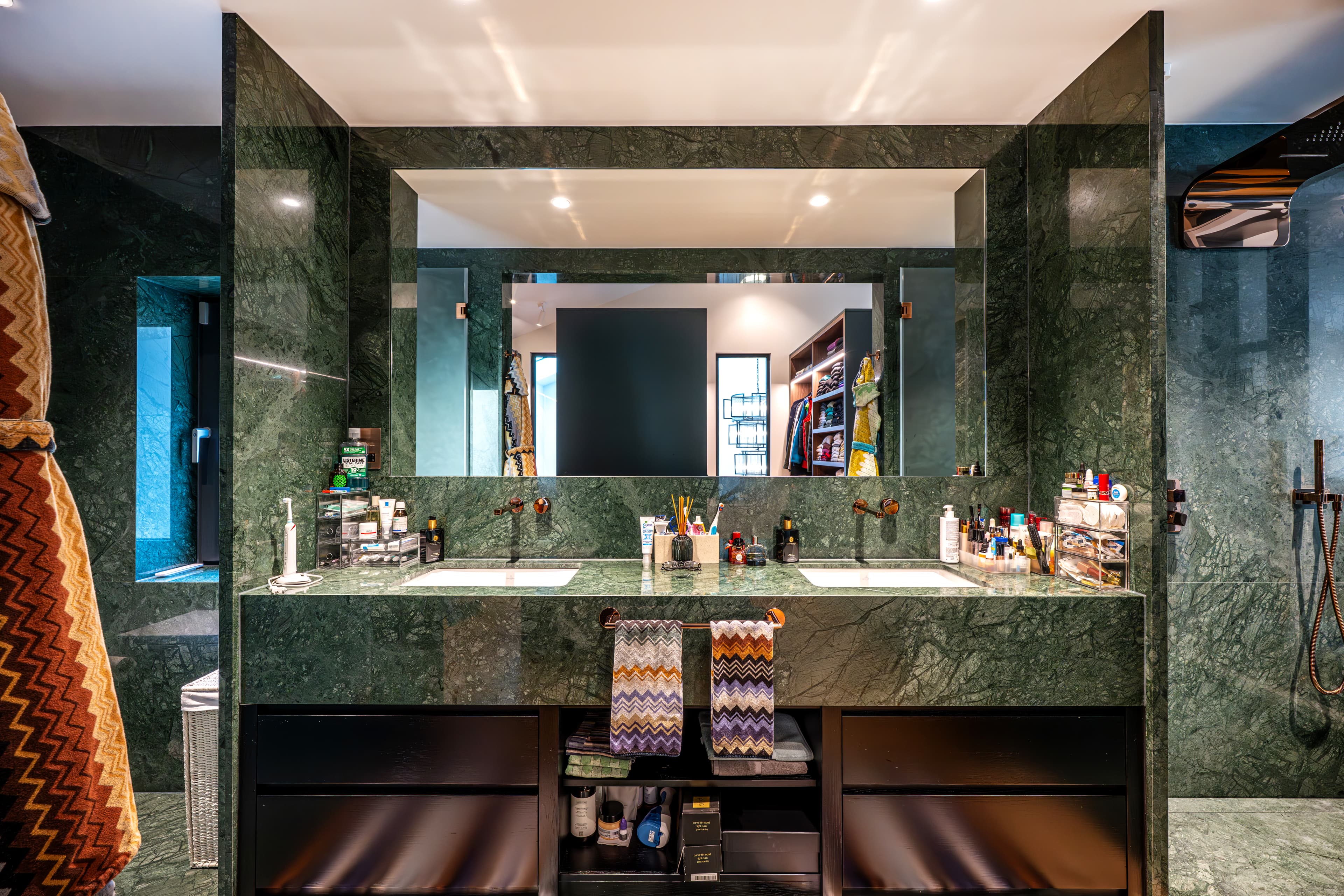 Elegant en suite bathroom with green marble double vanity, mirror wall and walk in shower